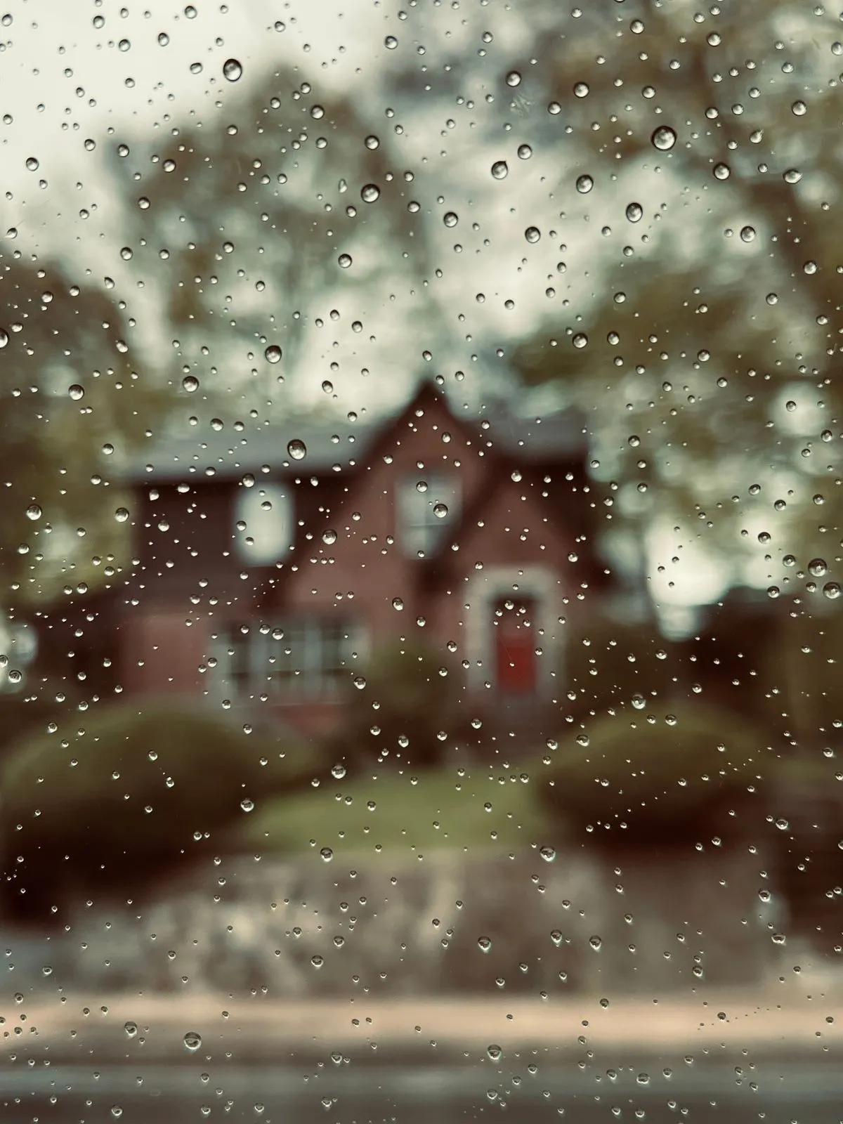 House seen through a rain-covered window during bad weather