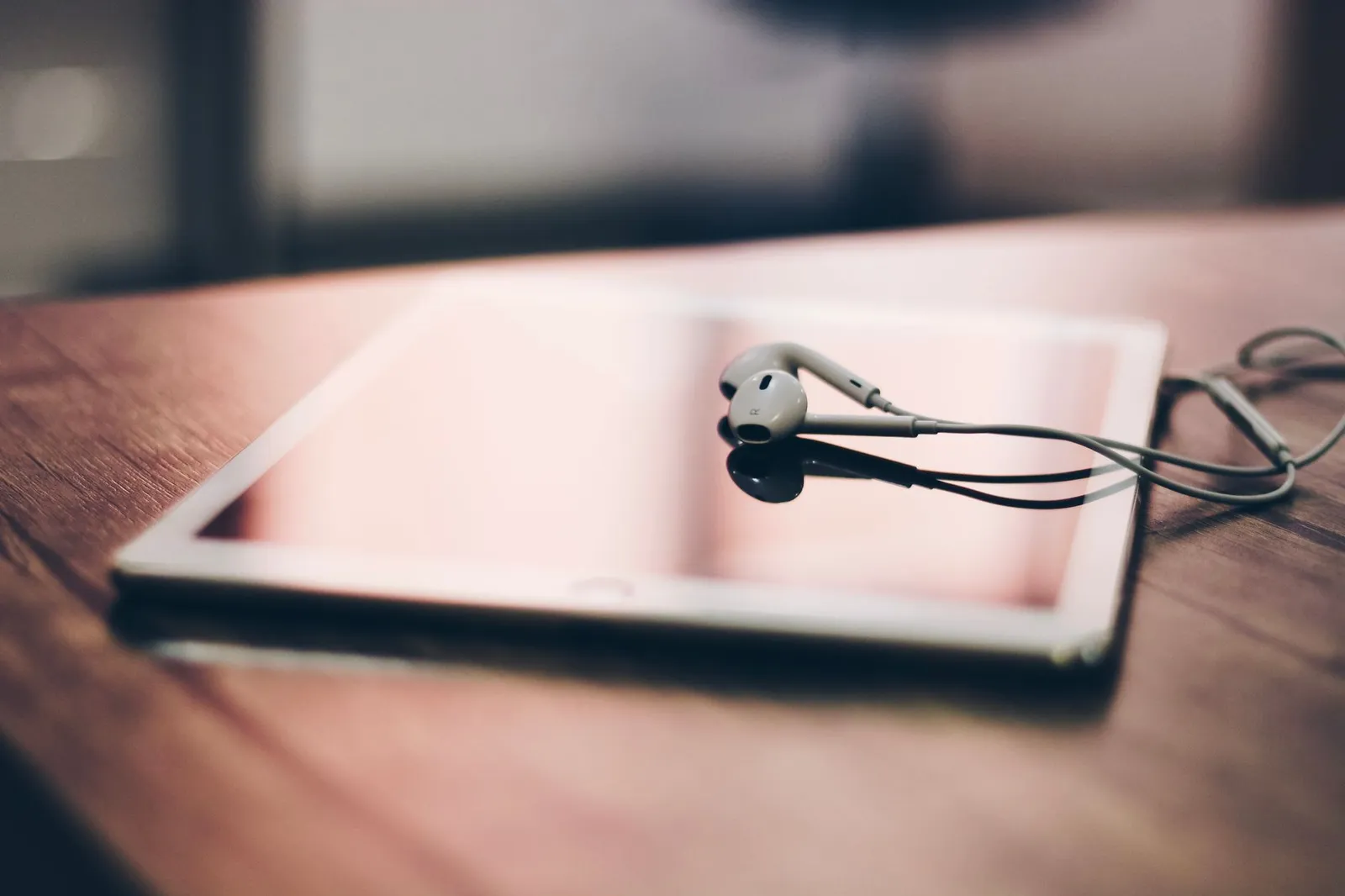 Tablet com auriculares pousado numa mesa de madeira
