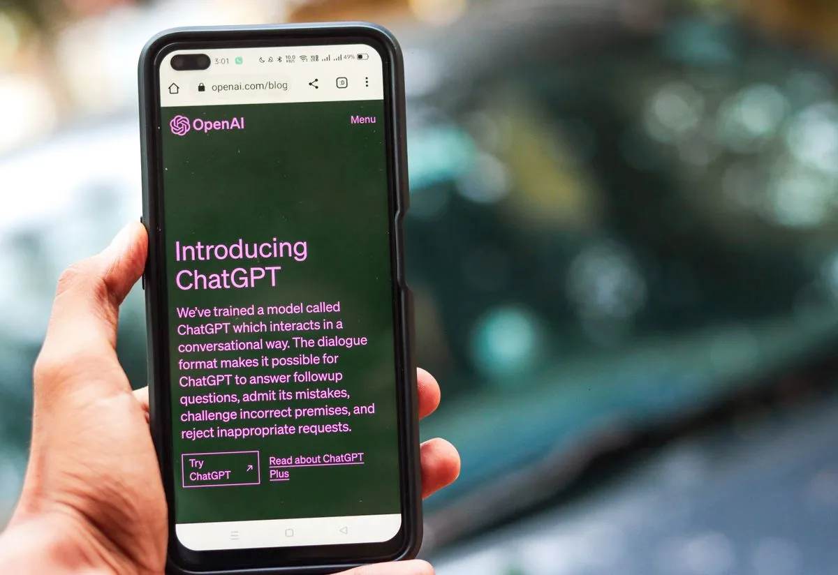 Hand holding a smartphone showing the ChatGPT page, illustrating a host connecting an AI assistant to Airbnb listings