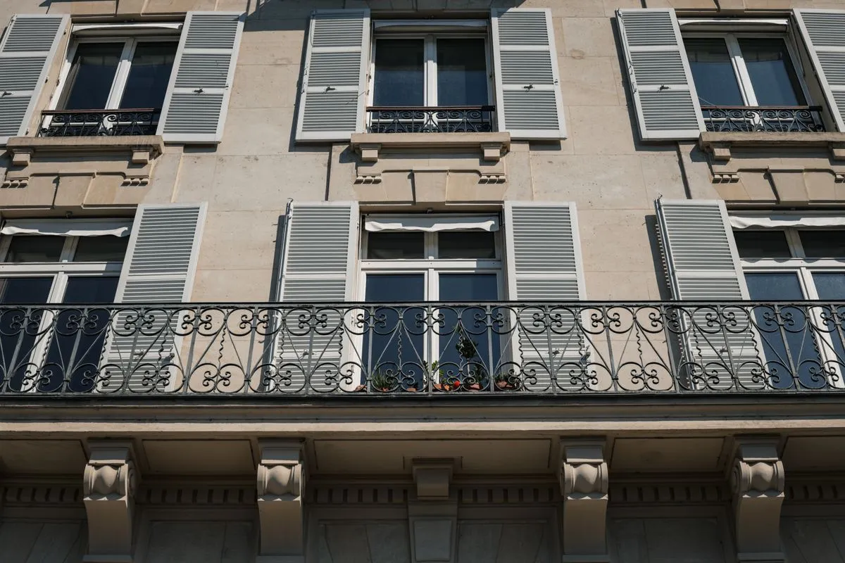 Parisian apartment building with grey shutters and wrought-iron balconies, the kind of home that needs a registration number to be rented to tourists
