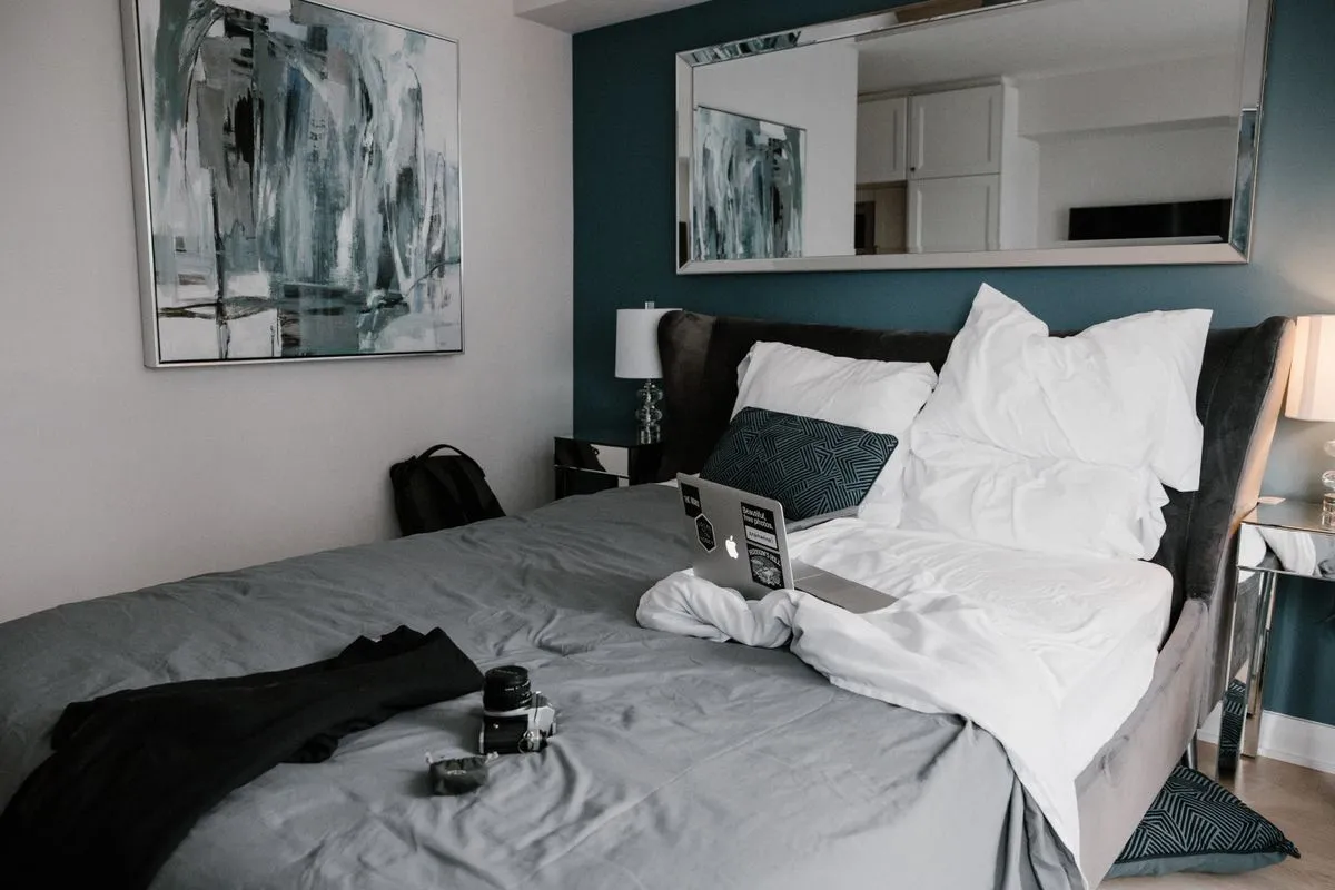 A short-term rental host reviewing a guest refund request message on a phone next to a laptop dashboard