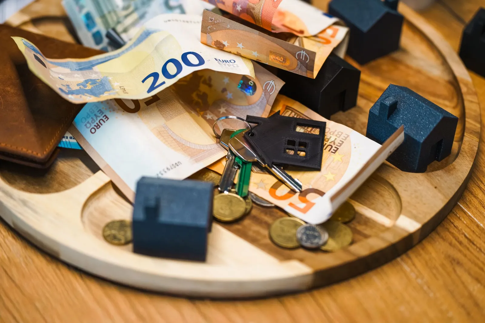 Billets en euros, clés et maisons miniatures représentant les revenus locatifs