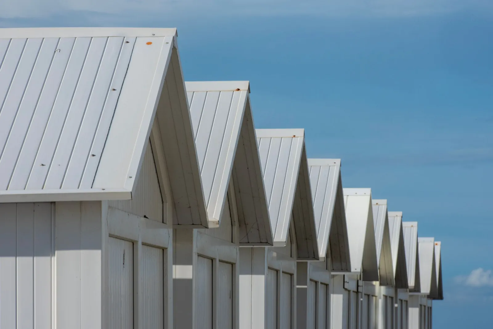 Reihe weißer Strandhütten unter blauem Himmel