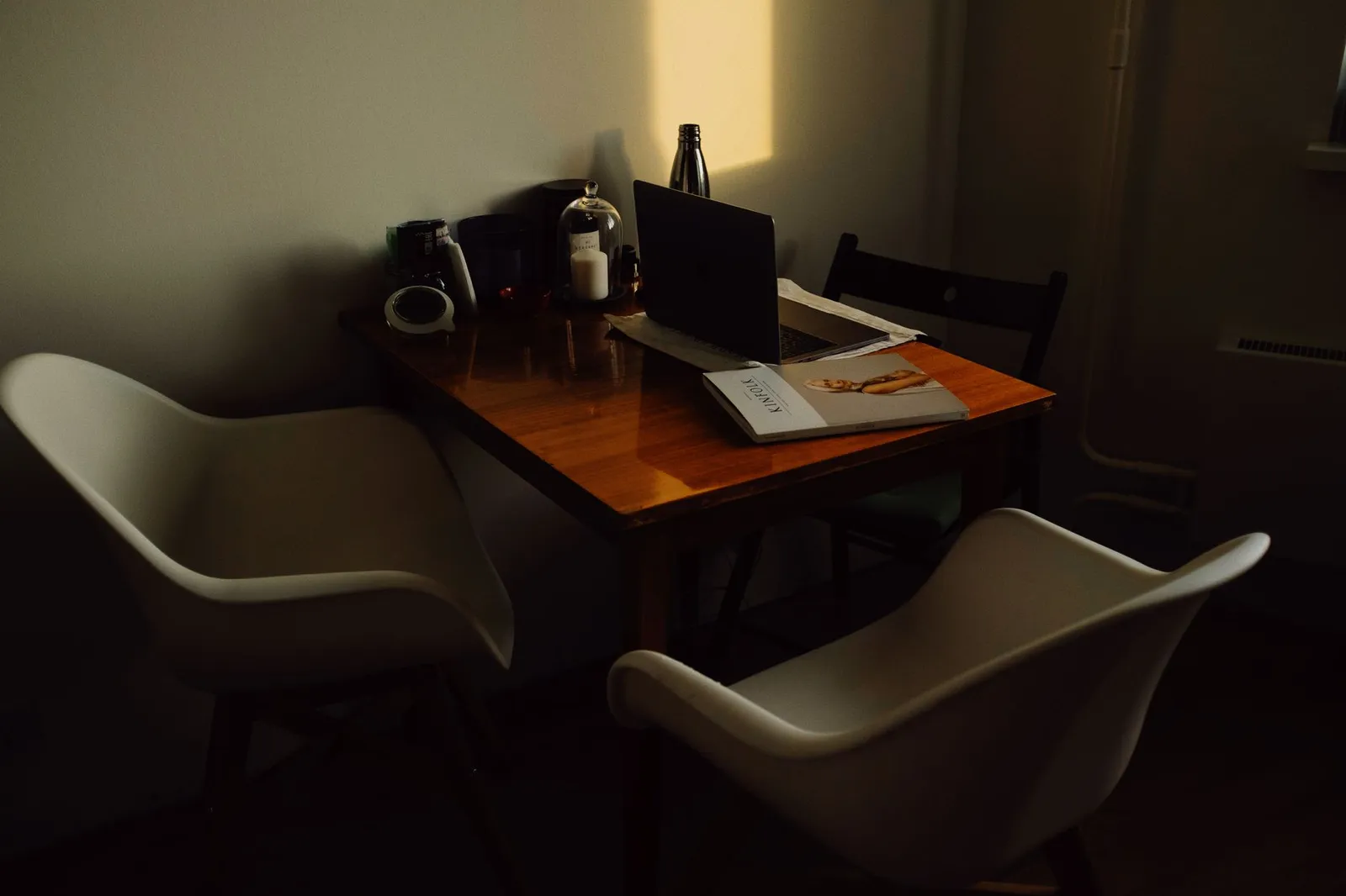 Laptop und Zeitschrift auf einem Holztisch in einem schwach beleuchteten Raum