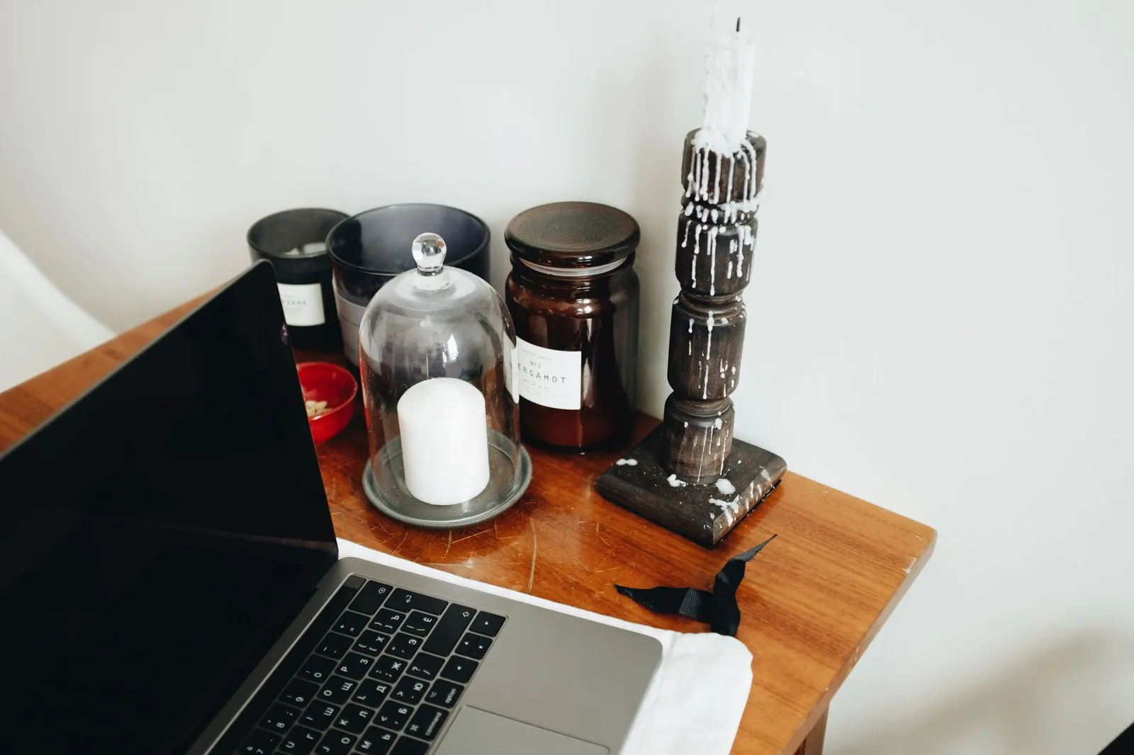 Portátil sobre un escritorio de madera junto a unas velas en una oficina en casa