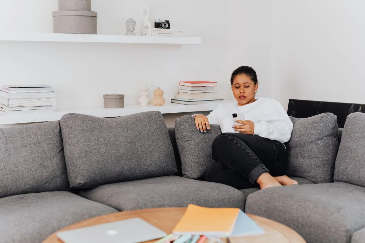 Traveller on a grey sofa searching for a place to stay on her smartphone