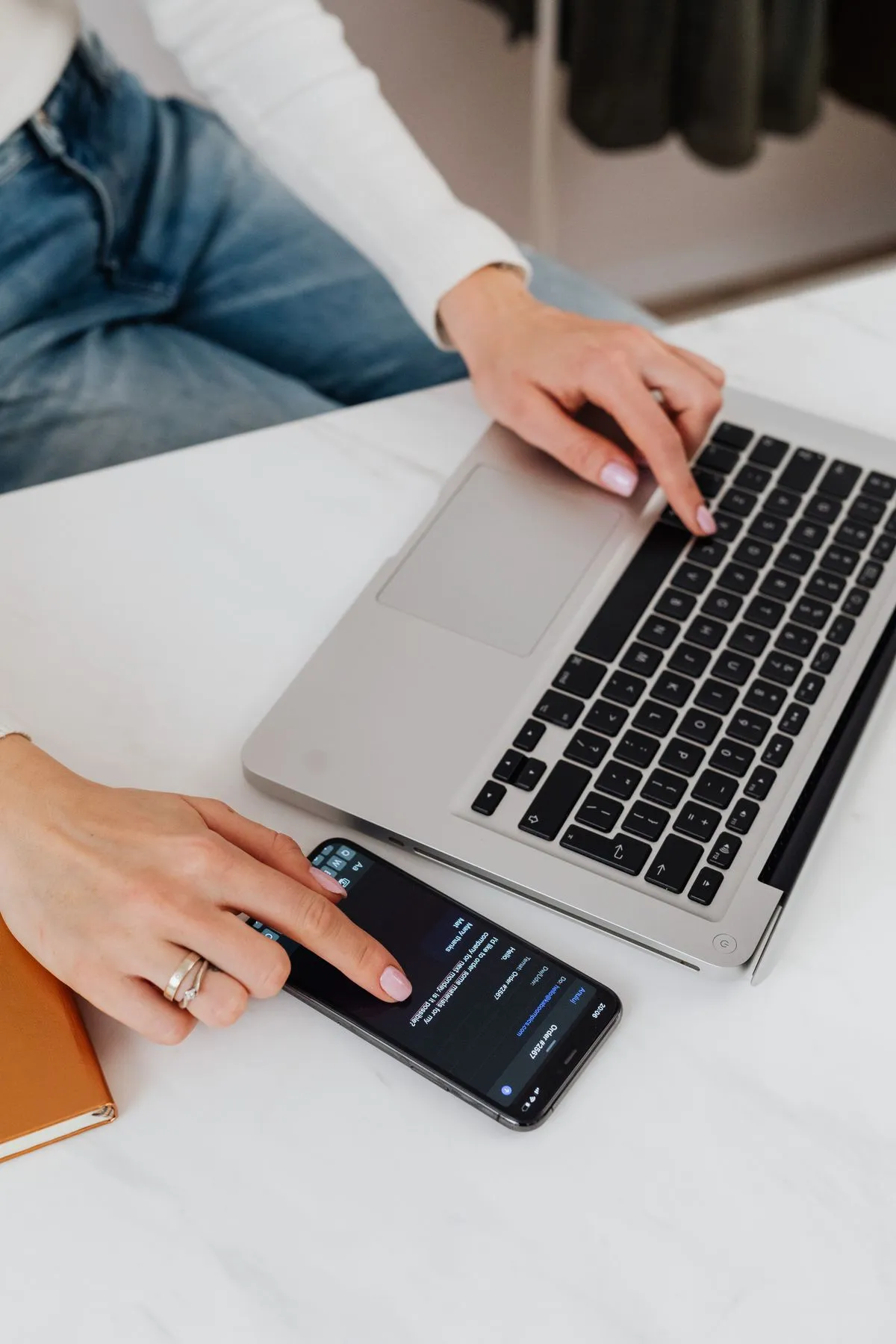 Host che usa contemporaneamente smartphone e portatile per gestire messaggi degli ospiti e annunci su due piattaforme di prenotazione