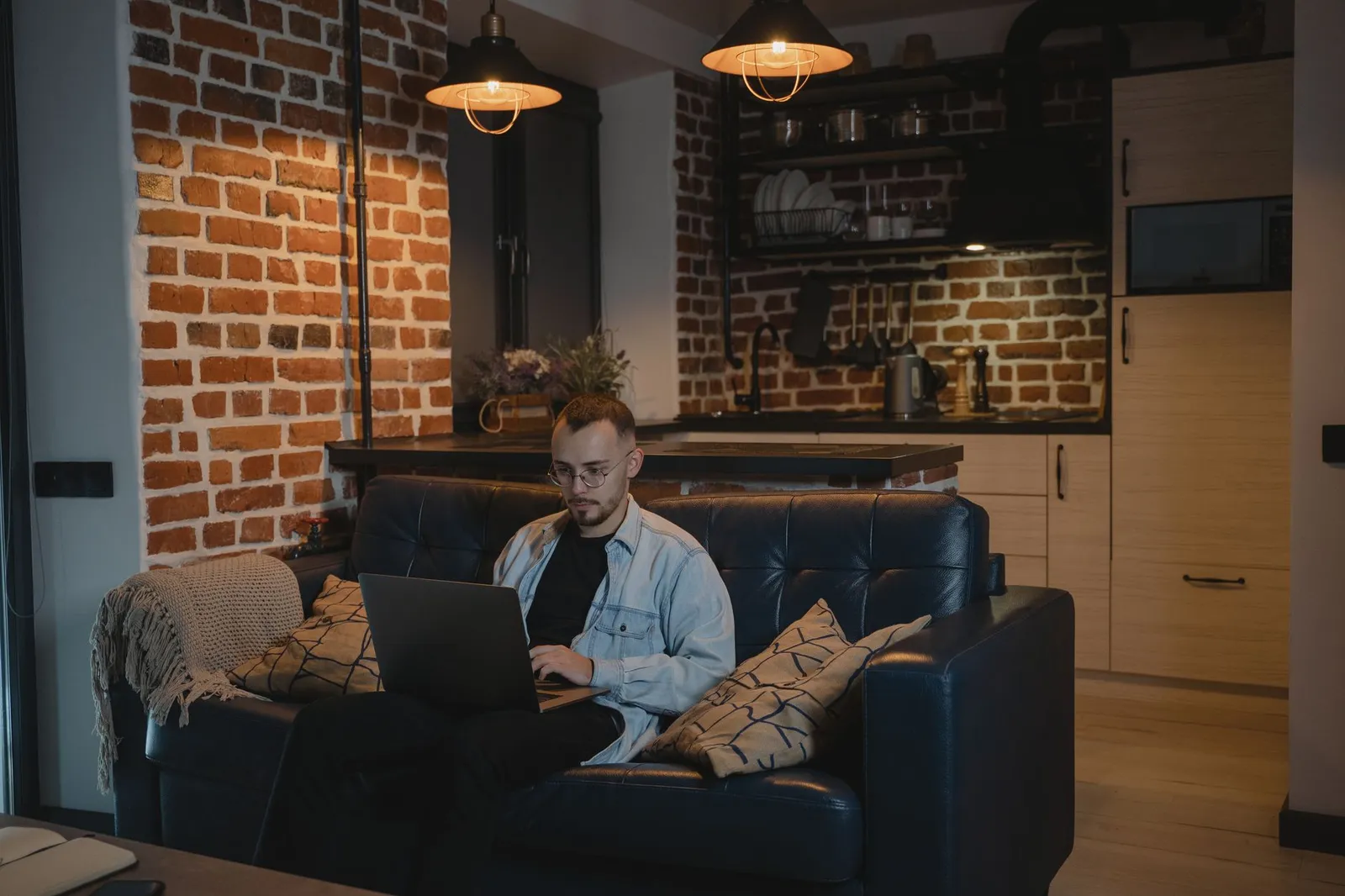 Lavoratore da remoto sul divano con il portatile in un loft