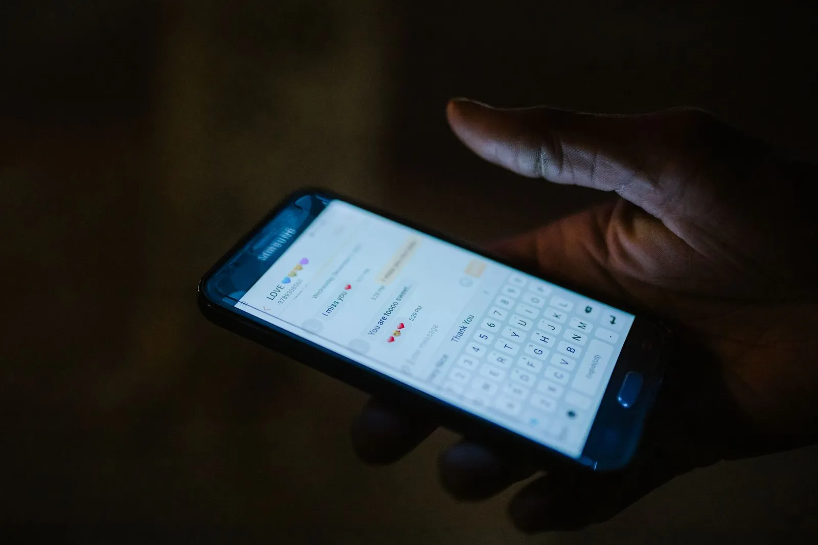 Mano sosteniendo un smartphone con una conversación de chat abierta