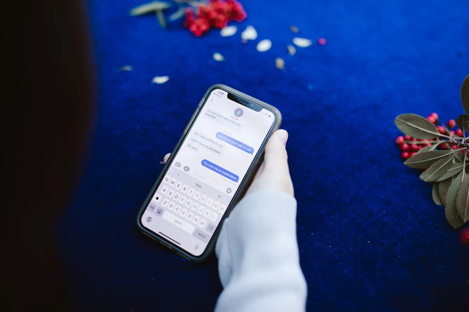Mão a segurar um smartphone com uma conversa de mensagens aberta
