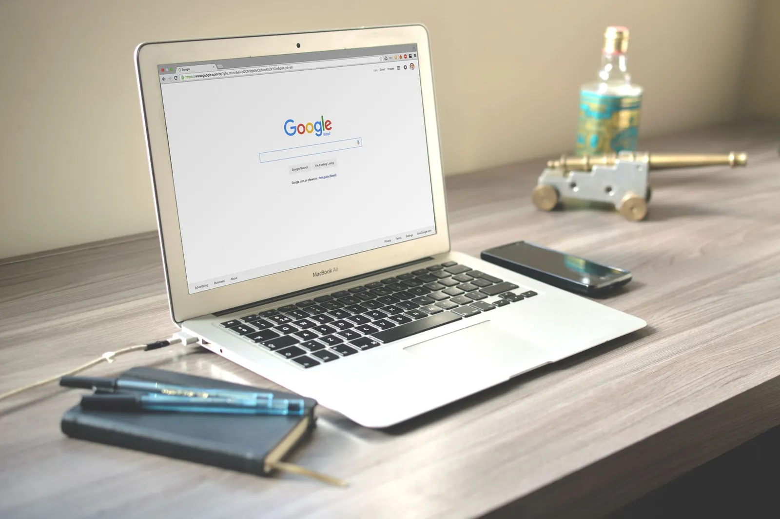 Laptop met een zoekmachine open naast een smartphone en notitieboek