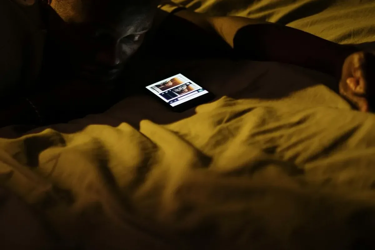 Una persona addormentata con il telefono che mostra i messaggi degli ospiti a tarda notte