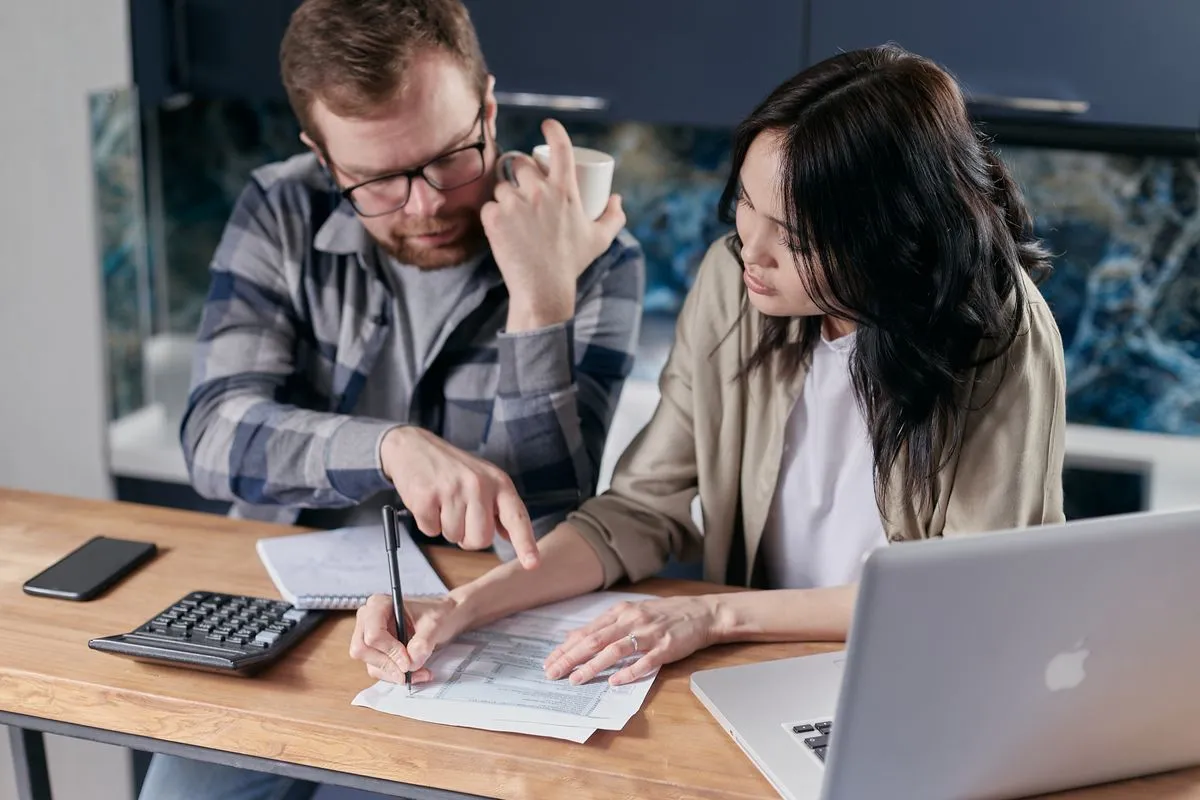Couple examinant ses revenus locatifs avec une calculatrice et un ordinateur pour comparer micro-BIC et régime réel