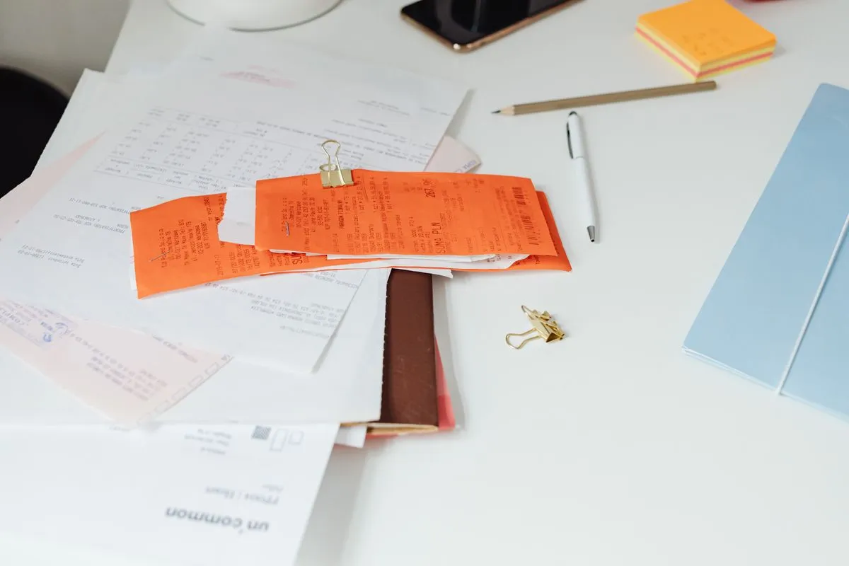 Pile de factures et de reçus sur un bureau, illustrant les factures d'une conciergerie aux propriétaires et aux voyageurs