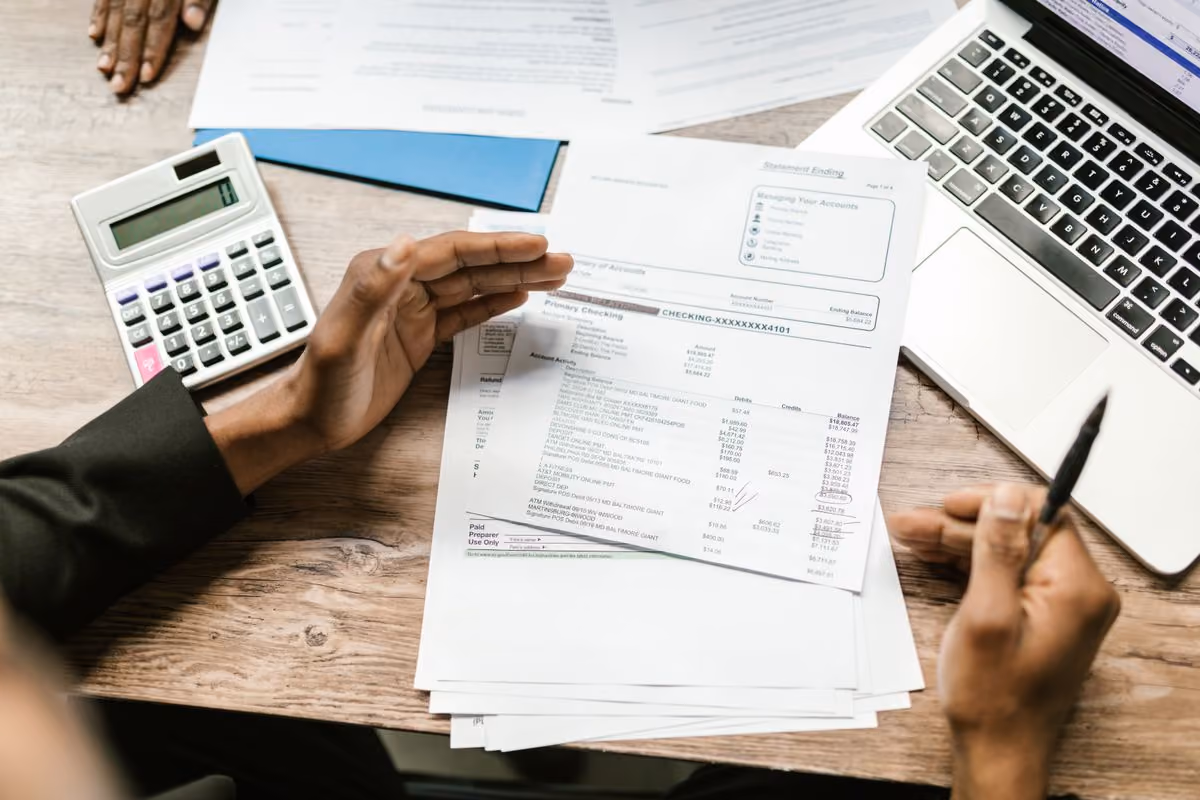 Host reviewing a statement next to a calculator and a laptop to check the commission charged by Booking.com