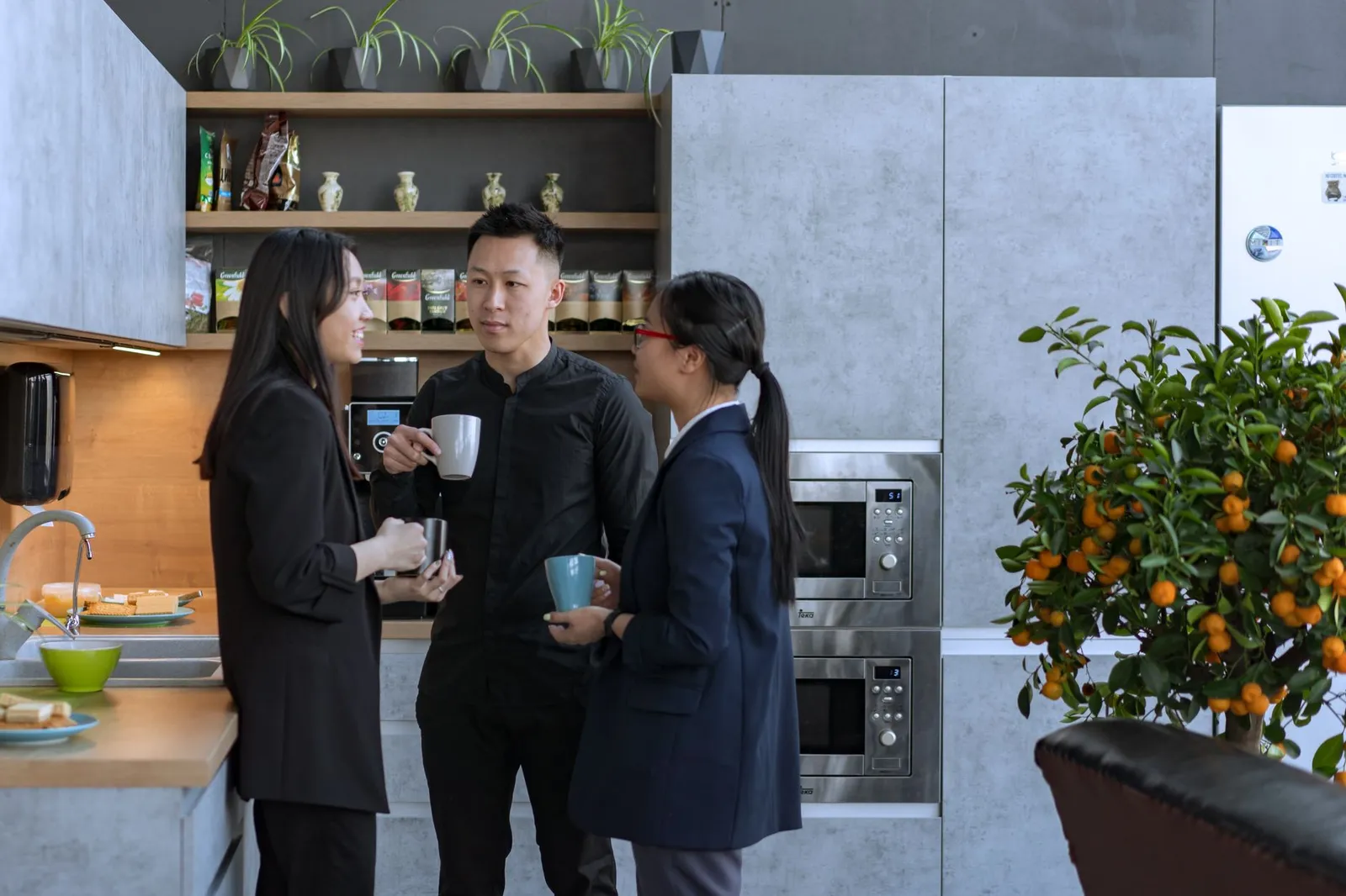 Tre colleghi in pausa caffè nella cucina di un ufficio