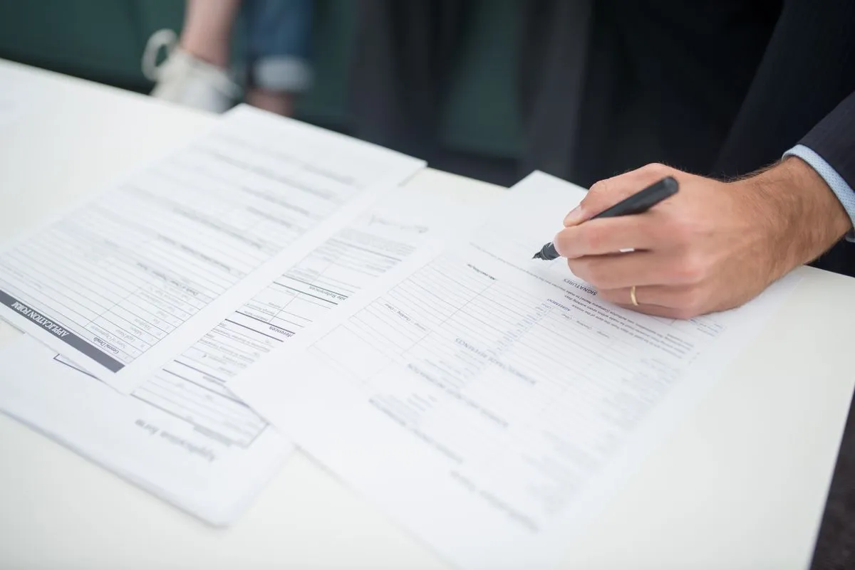 Hand signing insurance paperwork protecting a host