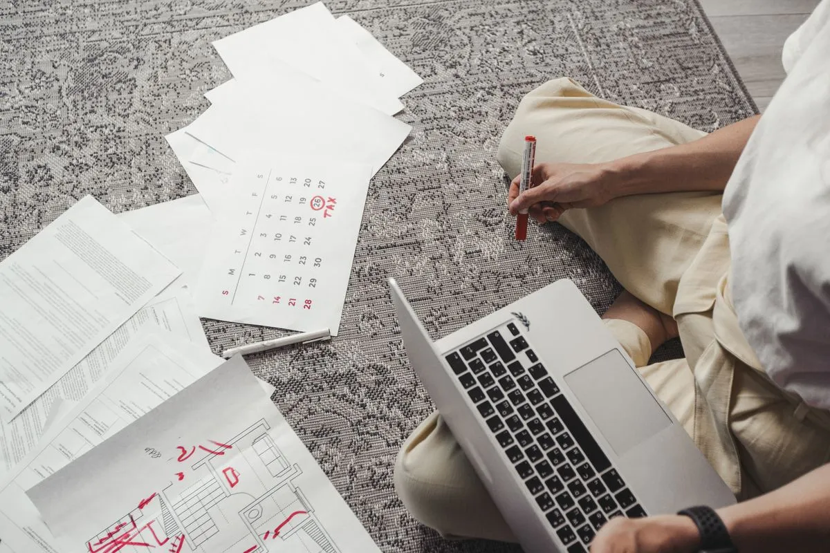 Host che pianifica i prezzi a notte su un portatile accanto a un calendario cartaceo con date cerchiate in rosso